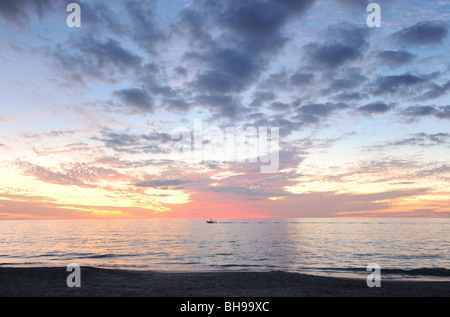 Ein einsamer Boot am Horizont unter einen Sonnenuntergang aus Neapel Strand Naples Florida USA Stockfoto