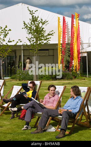 Menschen trinken und Buch setzte sich in Liegestühlen draußen in der Sonne Hay Festival 2009. Stockfoto