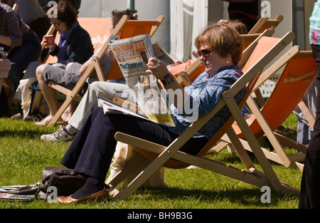 Frau saß im Liegestuhl lesen Zeitung draußen in der Sonne Hay Festival 2009. Stockfoto