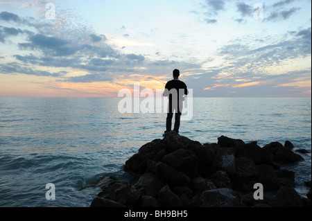 Einsamen Fischer stand auf Felsen gegen einen spektakulären Sonnenuntergang am Strand von Naples Florida USA Stockfoto