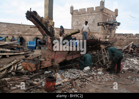 Schrotthändler arbeiten auf das Schiffswrack in den Hafen von Essaouira, durch die Stadtmauern geschützt Stockfoto