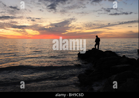 Einsamen Fischer stand auf Felsen gegen einen spektakulären Sonnenuntergang am Strand von Naples Florida USA Stockfoto