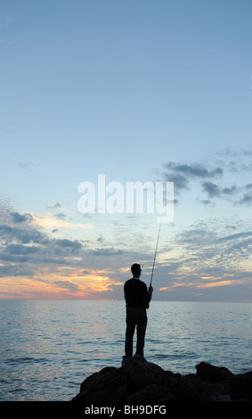 Einsamen Fischer stand auf Felsen gegen einen spektakulären Sonnenuntergang am Strand von Naples Florida USA Stockfoto