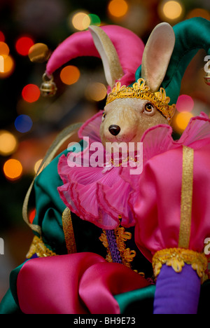 Ein Kaninchen Hofnarr Urlaub Dekoration vor einem beleuchteten Weihnachtsbaum. Stockfoto
