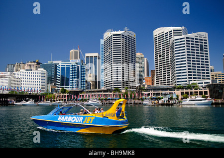 SYDNEY, Australien – Ein Touristenjet-Boot, das vom Darling Harbour in Cockle Bay aus mit der Skyline des Central Business District von Sydney im Hintergrund fährt. Stockfoto