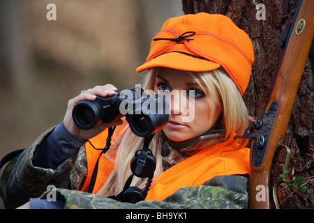 PORTRÄT JUNGE FRAU 21 Y.O WEIBLICHE JÄGER IM WALD TRAGEN ORANGE BLAZE STÜRMISCHEN KROMER HUT Stockfoto