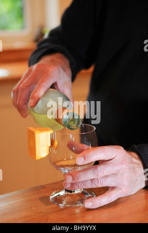 Blinder Mann Gießen gekühltem Weißwein in ein Glas mit einem bleeping flüssige Vermesser Verschütten in der Küche zu verhindern Stockfoto