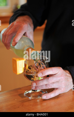 Blinder Mann Gießen gekühltem Weißwein in ein Glas mit einem bleeping flüssige Vermesser Verschütten in der Küche zu verhindern Stockfoto