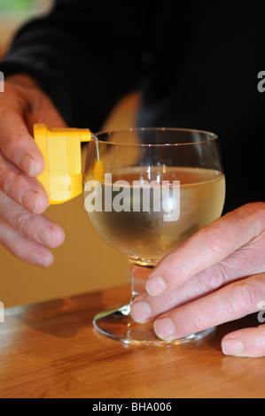Blinder Mann mit einem bleeping Flüssigkeitsstand, Weißwein in ein Glas gießen, unabhängiges Leben mit Sehbehinderung zu helfen Stockfoto