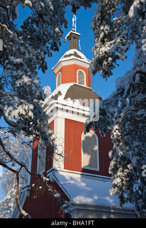 Alte hölzerne Kirche hinter gefrorenen eisigen verschneiten Bäumen in Hyvinkää, Finnland Stockfoto