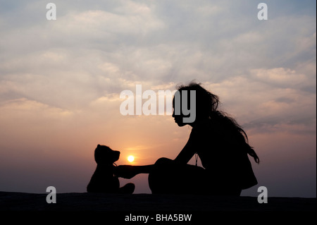 Indische Mädchen hält ihre Teddybären Pfote bei Sonnenuntergang. Silhouette. Indien Stockfoto