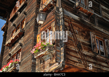 Traditionelle Schweizer Holzhaus / Chalet eingerichtet mit alten Ski und Geranien im Alpendorf Grimentz, Wallis, Schweiz Stockfoto