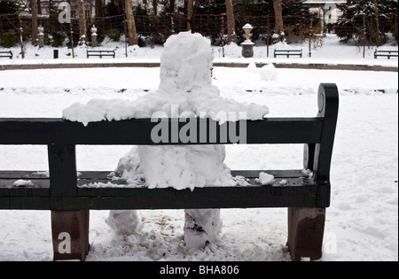Schneemann auf Parkbank sitzen Stockfoto