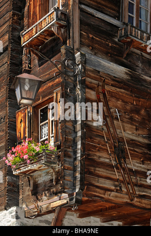 Vorderseite des traditionellen Holzhaus zieren alte Skier und Geranien im alpinen Dorf Grimentz, Wallis, Schweiz Stockfoto