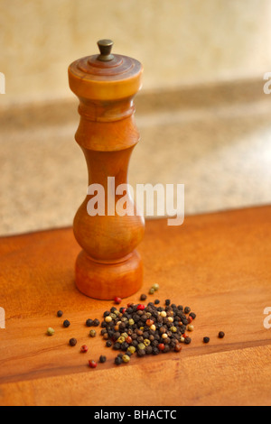 Gemischte getrocknete ganze Pfefferkörner mit einer Hand drehte Holz Pfeffermühle Stockfoto