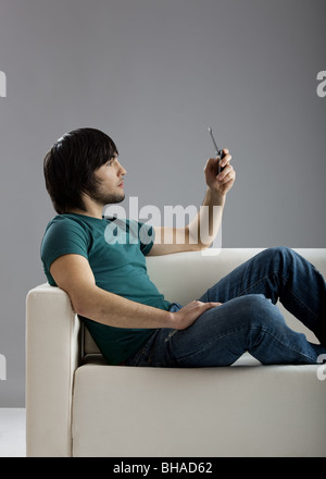 Gut aussehender junger Mann auf der Couch sitzen und sprechen am Handy Stockfoto