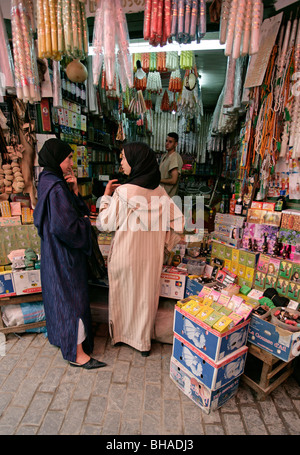 Zwei Frauen unterhalten vor eine Kerze und Weihrauch Stand entlang einer der vielen engen Gassen an der Kasbah in Tetuon, Marokko Stockfoto