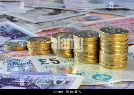 Fünf Stapel von ein Pfund-Münzen in Vergrößerung auf einem Hintergrund von fünf, zehn, zwanzig und fünfzig Pfund-Noten. Stockfoto