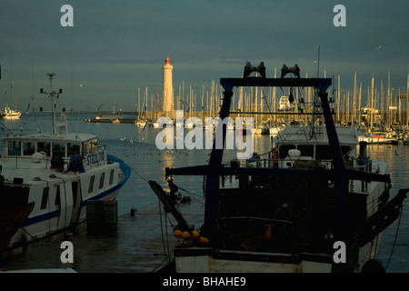 Im größten mediterranen Fischerhafen Sète, Frankreich sind Trawler ruhig vor Anker wie die Abendsonne den Leuchtturm erhellt Stockfoto