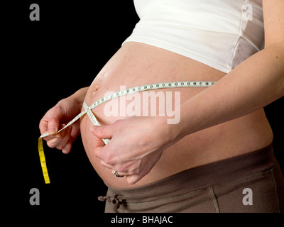 Schwangere Frau misst den Bauch mit einem Maßband Stockfoto