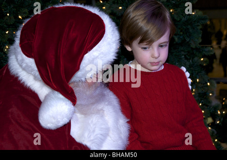 Junge sitzt mit dem Weihnachtsmann Stockfoto