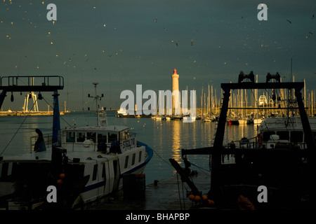 Im größten mediterranen Fischerhafen Sète, Frankreich sind Trawler ruhig vor Anker wie die Abendsonne den Leuchtturm erhellt Stockfoto