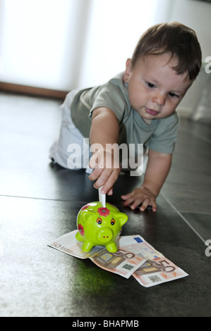 Baby Boy, Geld in das Sparschwein Stockfoto