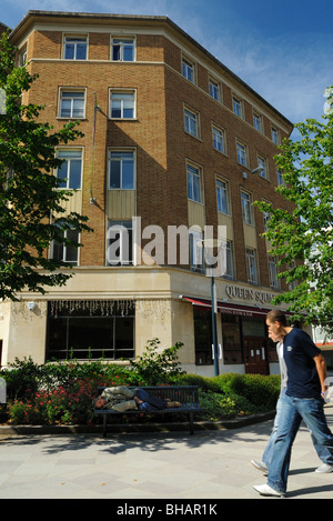 Zwei Männer Weitergabe ein Landstreicher schlafend liegen auf einer Bank in einer wohlhabenden Stadt Straße an einem sonnigen Tag. Stockfoto