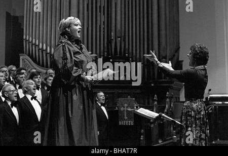 Eine Opern-Diva singt mit offenem Mund begleitet von einem walisischen Männerchor während einer Probe in der St. Pauls Kirche, Newport Stockfoto