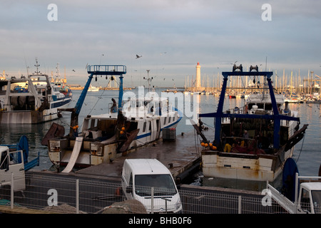 Im größten mediterranen Fischerhafen Sète, Frankreich sind Trawler ruhig vor Anker wie die Abendsonne den Leuchtturm erhellt Stockfoto