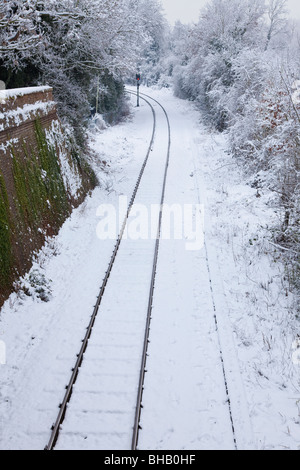 Schneebedeckten Eisenbahnschienen und eine rote Ampel an einer Biegung Stockfoto