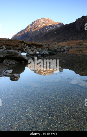 Die Westwand des Tryfan, ein Berg in Snowdonia, Wales, im Abendlicht getaucht und spiegelt sich in den Gewässern des Llyn Idwal Stockfoto