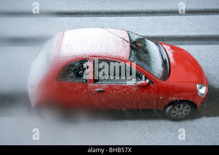 Rotes Auto in der Straße im Schnee Stockfoto