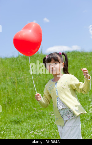 Japan, Tokyo Präfektur, Mädchen hält Herz geformt Ballon Stockfoto