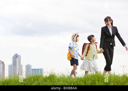 Japan, Tokyo Präfektur, Mutter und Kinder zu Fuß durch Wiesen, Hochhäuser im Hintergrund Stockfoto