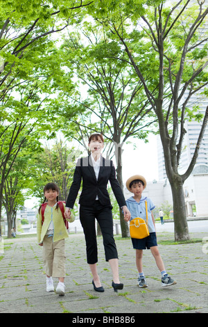 Japan, Tokyo Präfektur, Mutter und Kinder zu Fuß durch Weg von Bäumen gesäumt, Lächeln Stockfoto