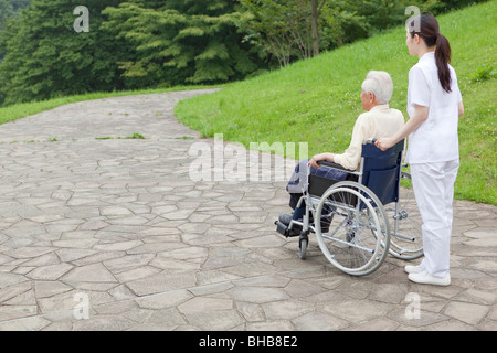 Japan, Tokyo Präfektur, Weiblich Krankenschwester drängen senior Mann im Rollstuhl Stockfoto