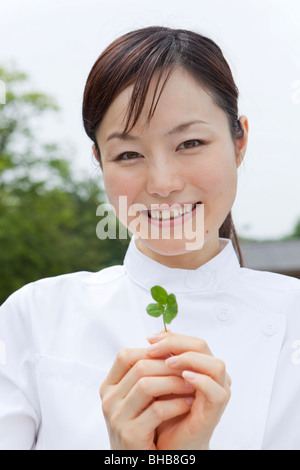 Japan, Tokyo Präfektur, Krankenschwester hält vier blätterte Klee, Lächeln, Porträt, Nahaufnahme Stockfoto