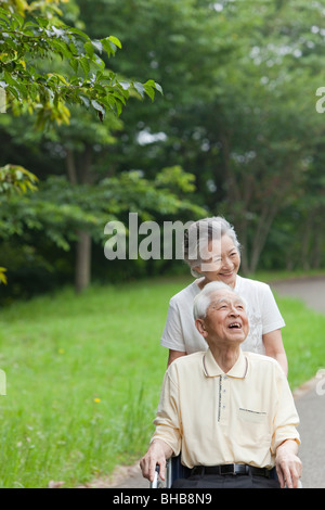 Japan, Tokyo Präfektur, älteres Paar im Park, Mann sitzt im Rollstuhl, nachschlagen, Lächeln Stockfoto