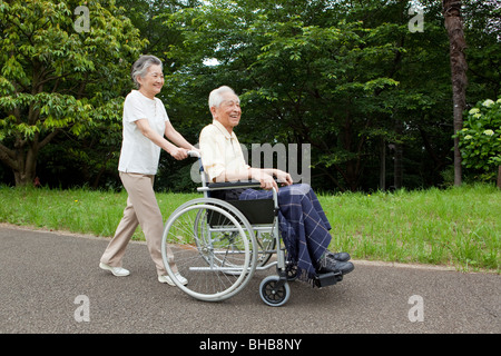 Japan, Tokyo Präfektur, Senior Frau schob senior Mann im Rollstuhl, Lächeln Stockfoto