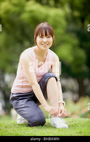 Japan, Osaka Präfektur, Frau Schnürsenkel binden, Lächeln, Porträt Stockfoto