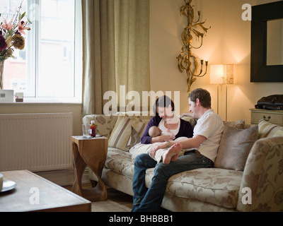 Ein paar und neues Baby sitzt auf einem sofa Stockfoto