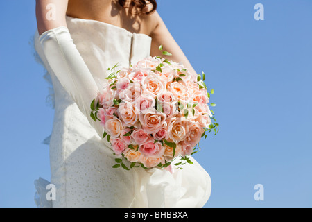 eine Braut hält Blumenstrauss hinter ihrem Rücken Stockfoto