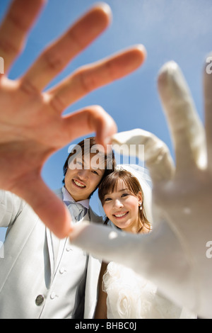 Porträt eines lächelnden Braut und Bräutigam ein Herzsymbol mit ihren Händen machen Stockfoto