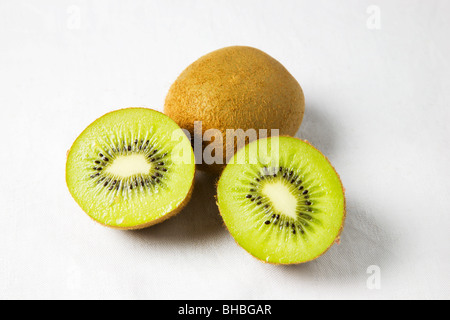 Ganze und halbierte Kiwis auf weißem Hintergrund Stockfoto