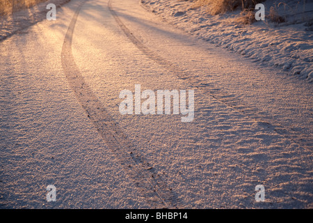 Autoreifen Spuren auf den ersten Schnee bei Sonnenuntergang, Finnland Stockfoto