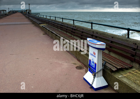 Eine R.N.L.I.-Sammelkiste angekettet an Sitzgelegenheiten auf Deal Pier in Kent. Stockfoto