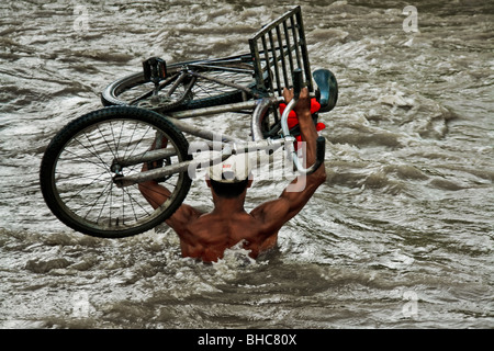 Eine kolumbianische Benzin Schmuggler mit seinem Fahrrad in der Mitte des Flusses Táchira an der kolumbianischen-venezolanischen Grenze. Stockfoto