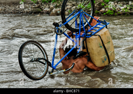 Eine kolumbianische Benzin Schmuggler mit seinem Fahrrad in der Mitte des Flusses Táchira an der kolumbianischen-venezolanischen Grenze. Stockfoto