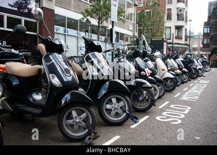 Eine Reihe von Motorroller angekettet und gesichert auf einem Parkplatz im Zentrum von London Stockfoto